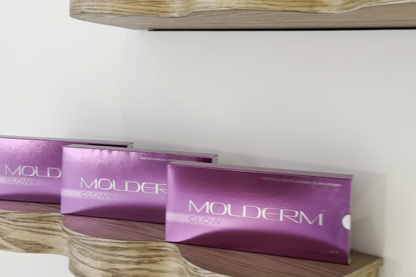 Förpackningar med MOLDERM GLOW på hyllan i GLONA Estetisk Hälsas lokal
